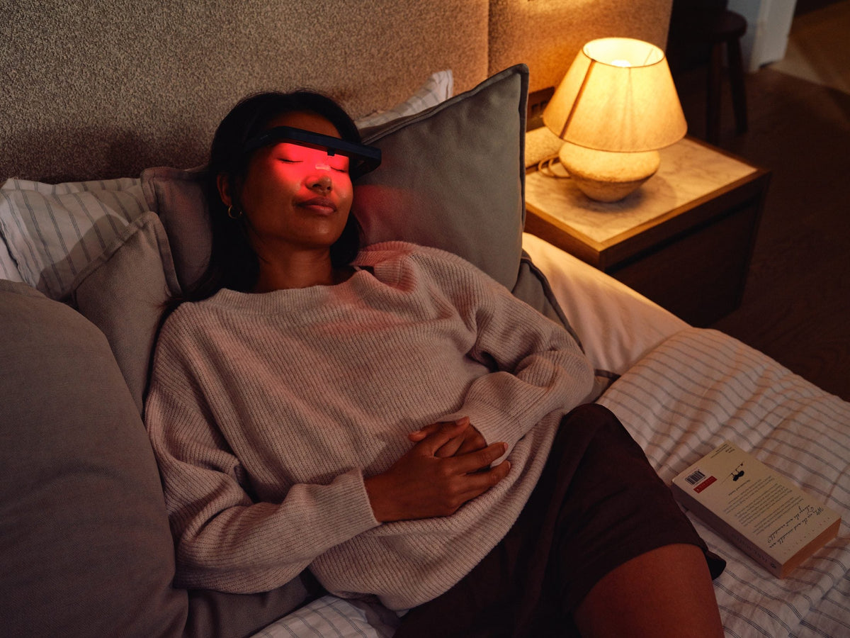 Halo light therapy glasses glowing red while a woman relaxes in bed